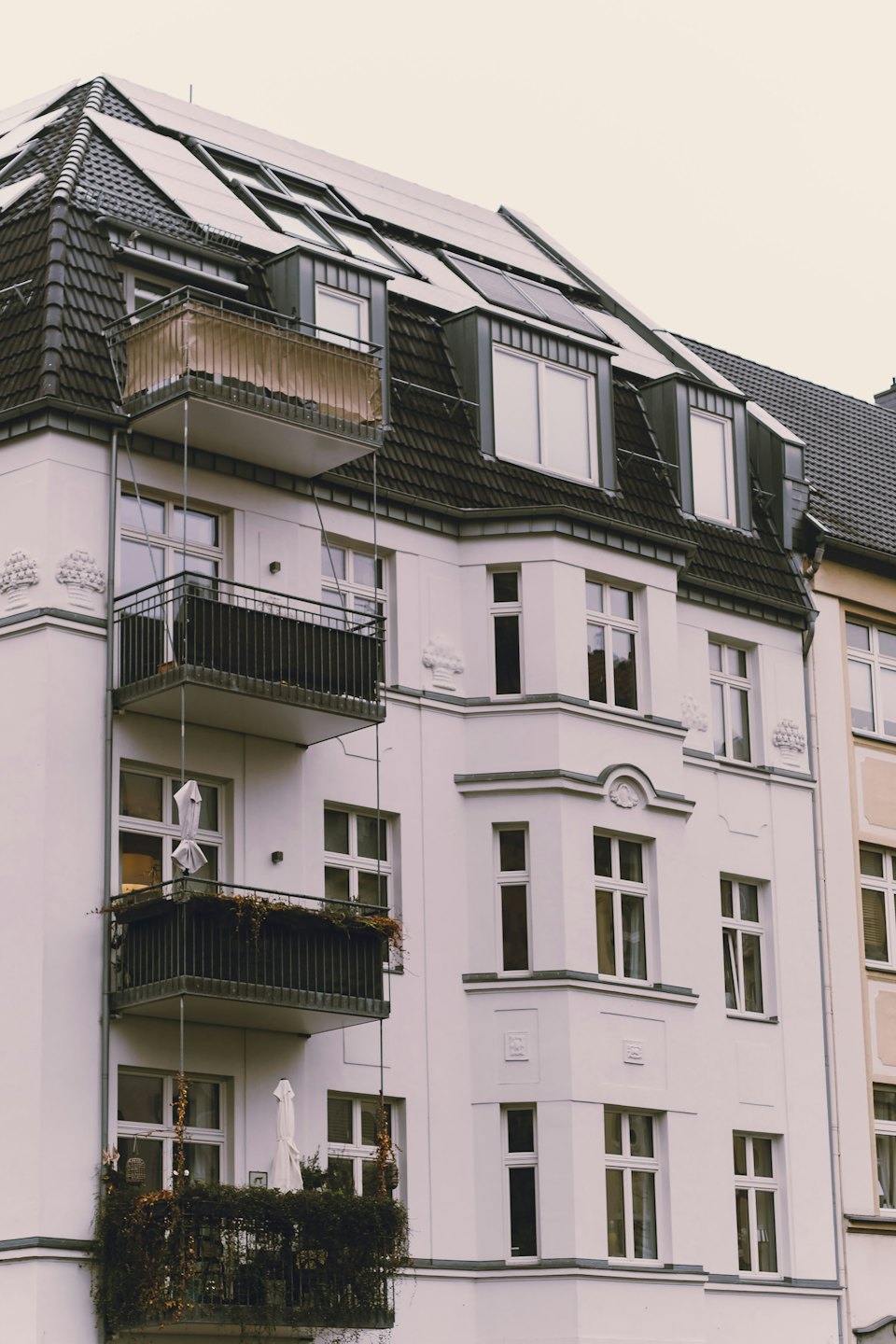 Immeuble résidentiel avec balcons ornés et panneaux solaires sur le toit.