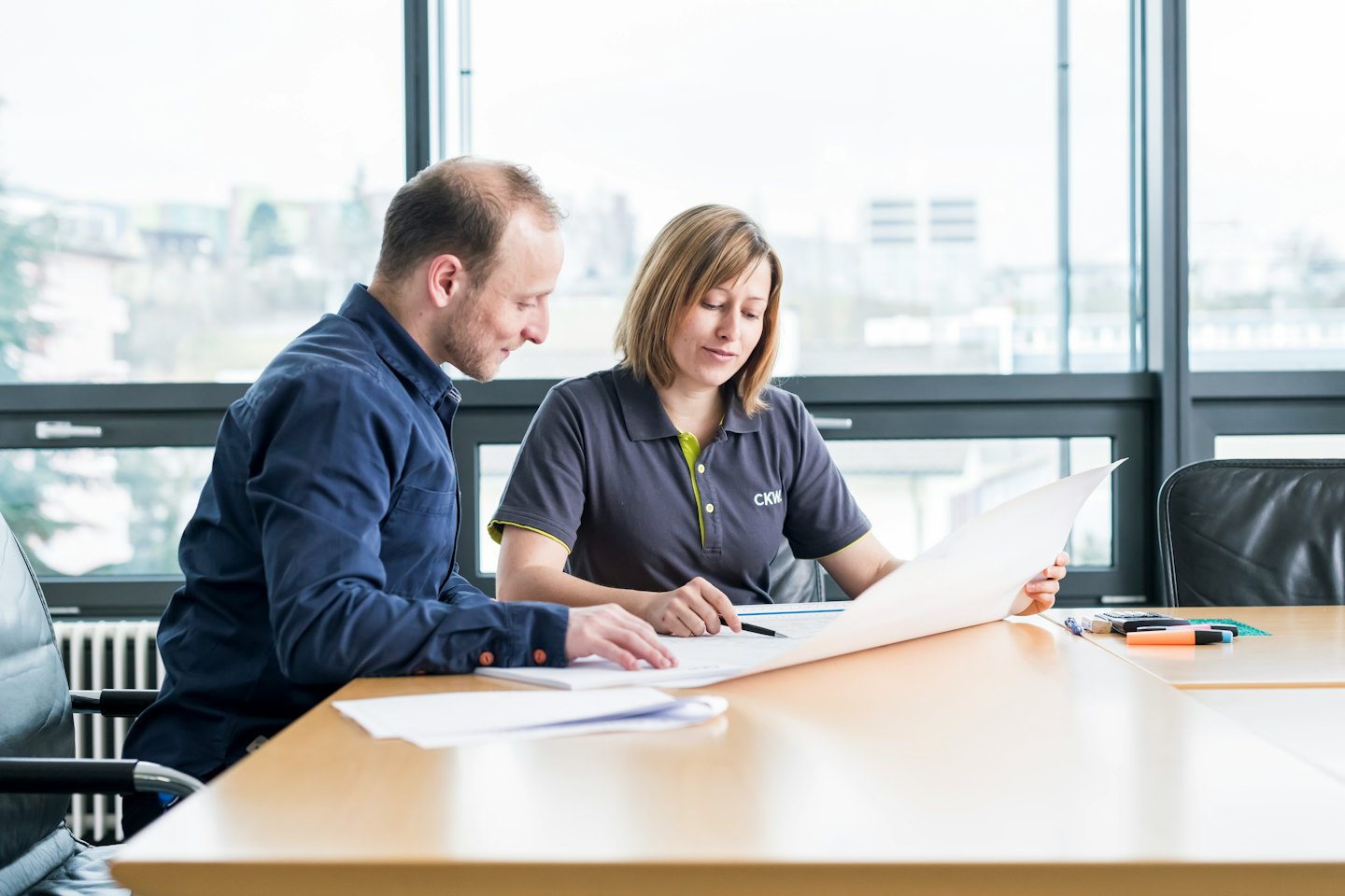 Deux professionnels discutent des plans sur une table de conférence.